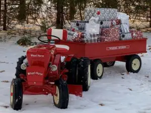 Red tractor with presents in winter landscape.