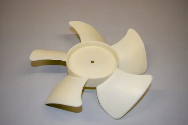 A white plastic fan with four blades on top of it.