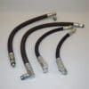 A set of four hoses are sitting on the floor.