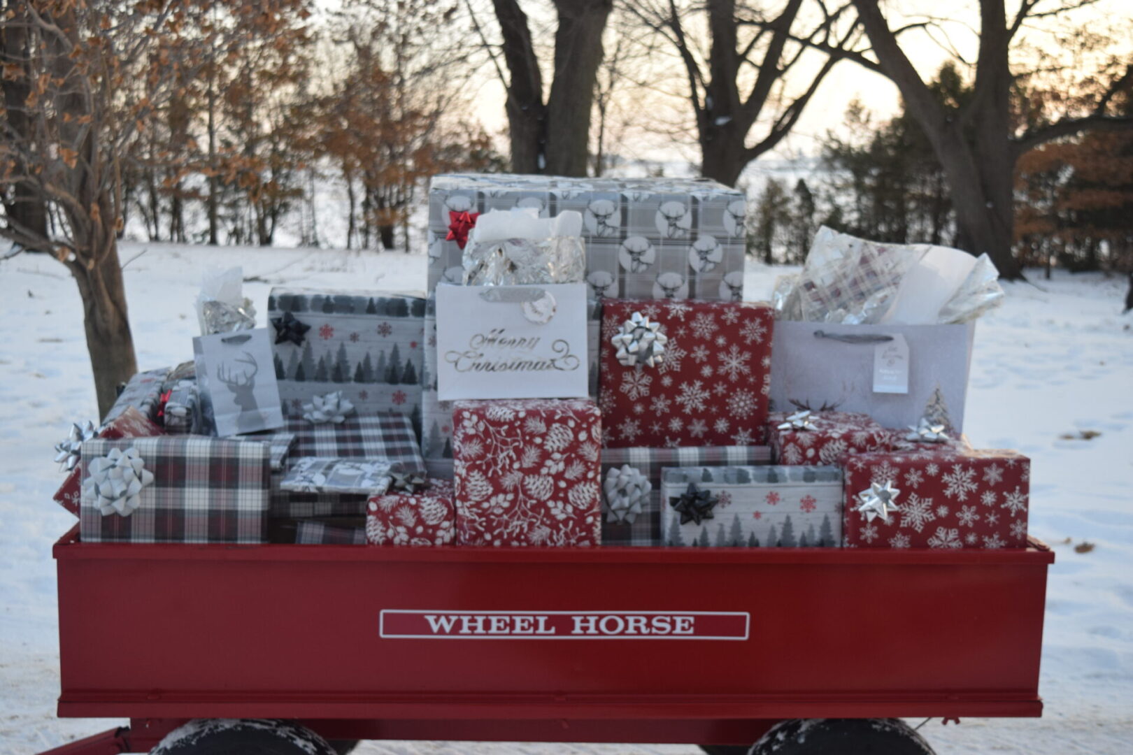 A red wagon full of christmas presents on a snowy day displayed in a gallery.