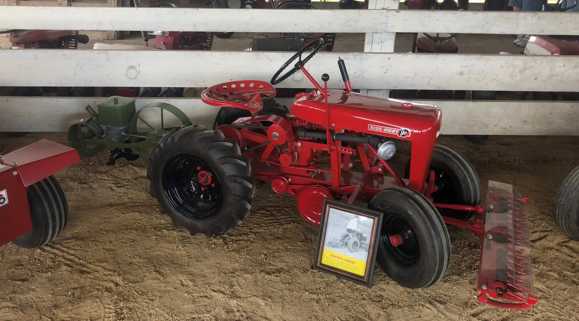 A red tractor is parked in the dirt.