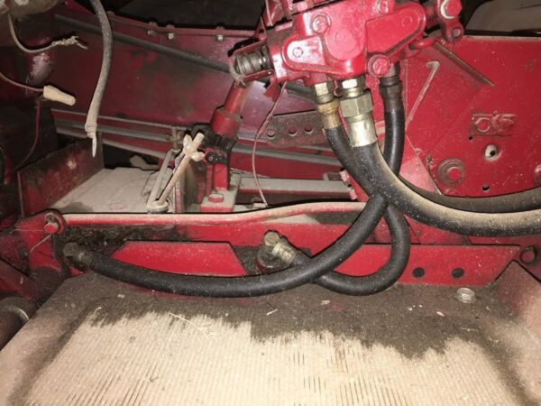A red tractor with two hoses attached to it.