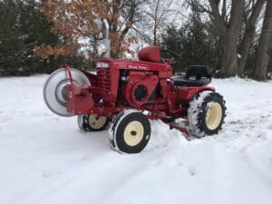 A red tractor sitting in the snow, showcased in a gallery setting.