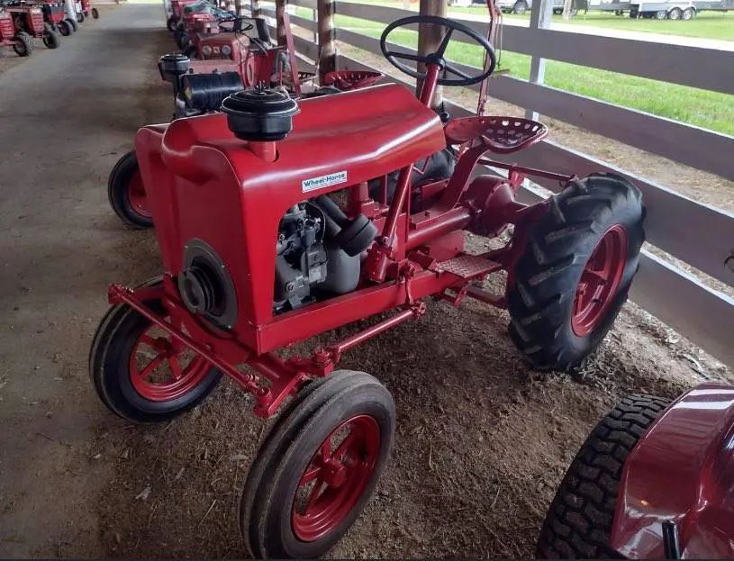 A red tractor is parked in a barn-gallery.