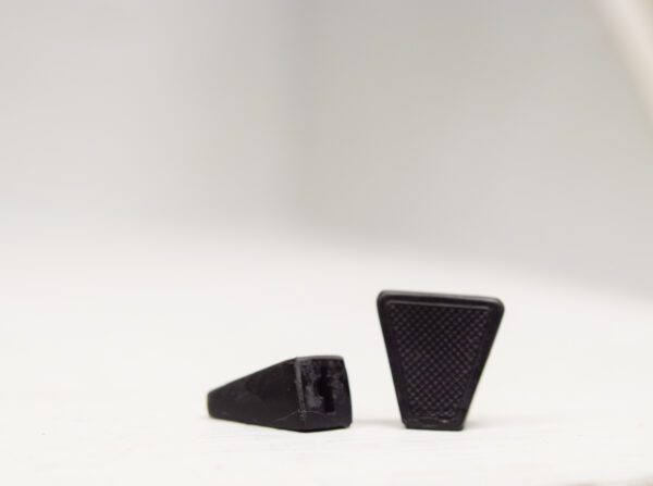 A pair of black plastic foot rests on top of a white surface.