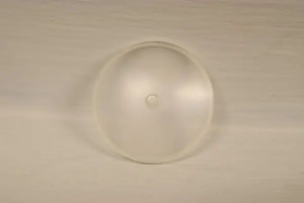 A small white circle on a white surface, acting as a Replacement Fuel Cap Indicator Lens.