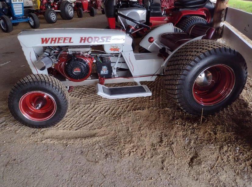 A white and red wheel horse tractor parked in the sand.