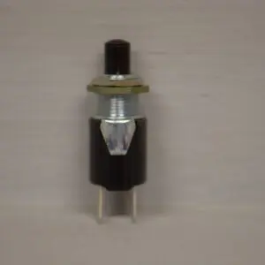 A small black Toro Wheel Horse replacement push button switch on a white surface.