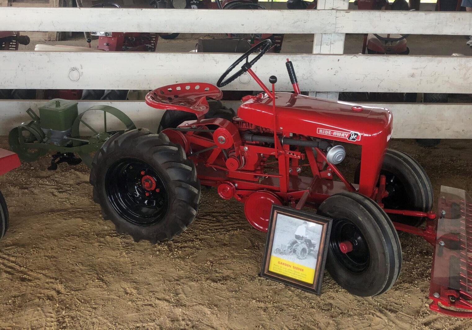 A red tractor is parked in the dirt.